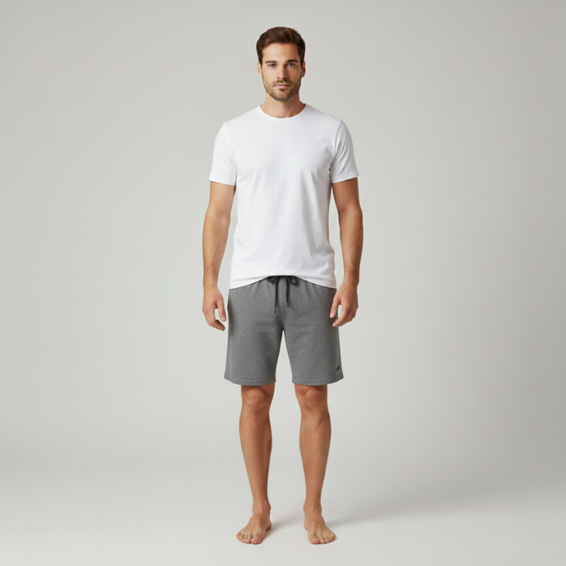 Man wearing a white t-shirt and gray shorts on a plain background