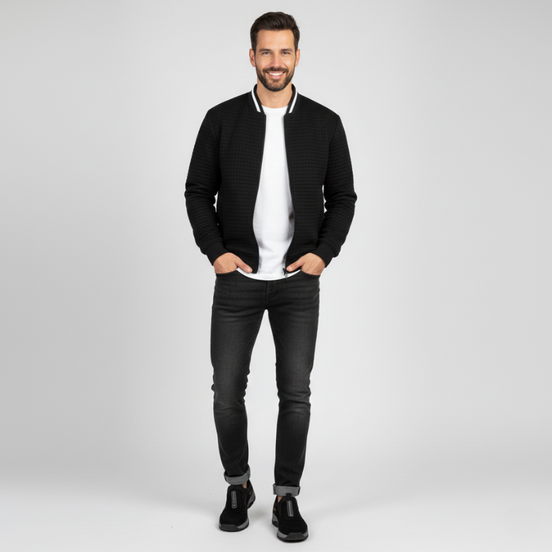 Man wearing a black textured jacket, white shirt, and black jeans on a light gray background