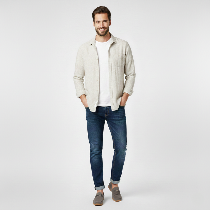 Man wearing a light-colored jacket, white shirt, blue jeans, and brown shoes on a white background