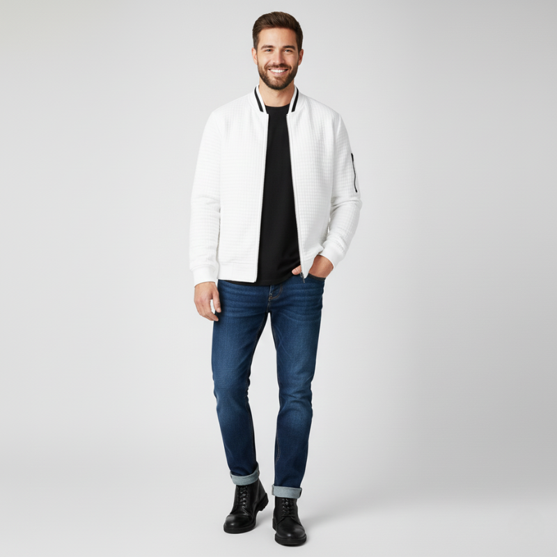 Man wearing a white jacket, black shirt, blue jeans, and black boots on a light gray background