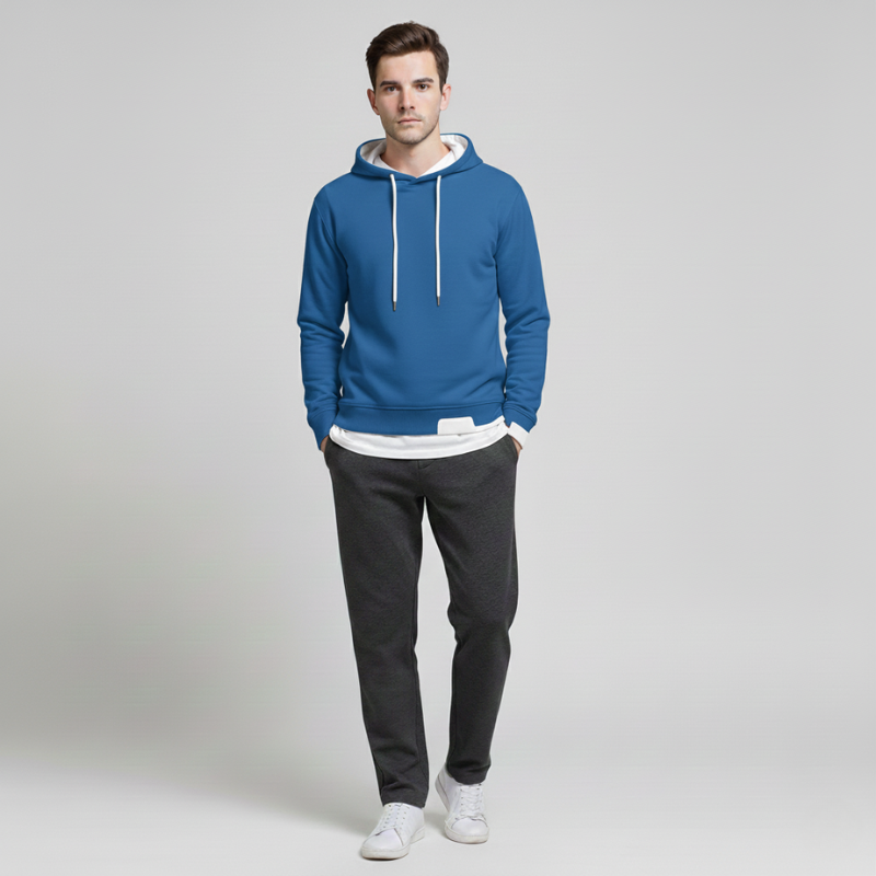 Man wearing a blue hoodie and black pants on a light gray background