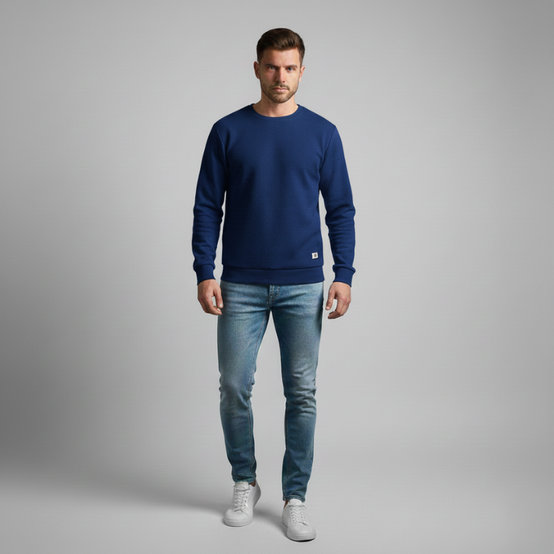 Man wearing a blue sweatshirt and jeans on a gray background
