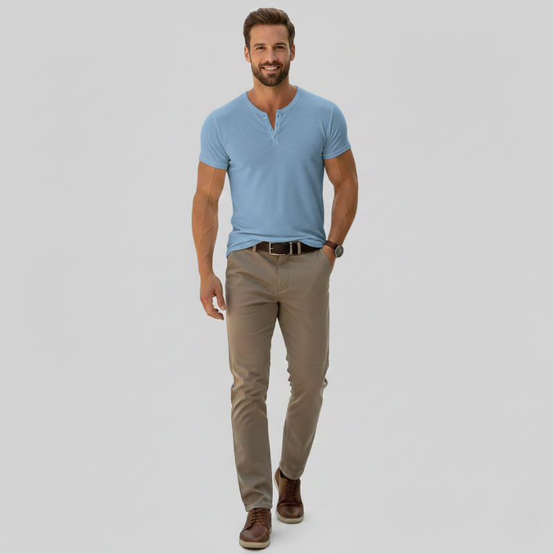 Man wearing a light blue shirt and beige pants on a gray background