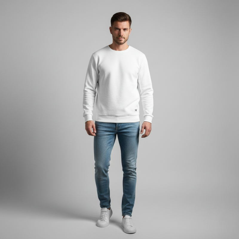 Man wearing a white sweater and blue jeans on a gray background