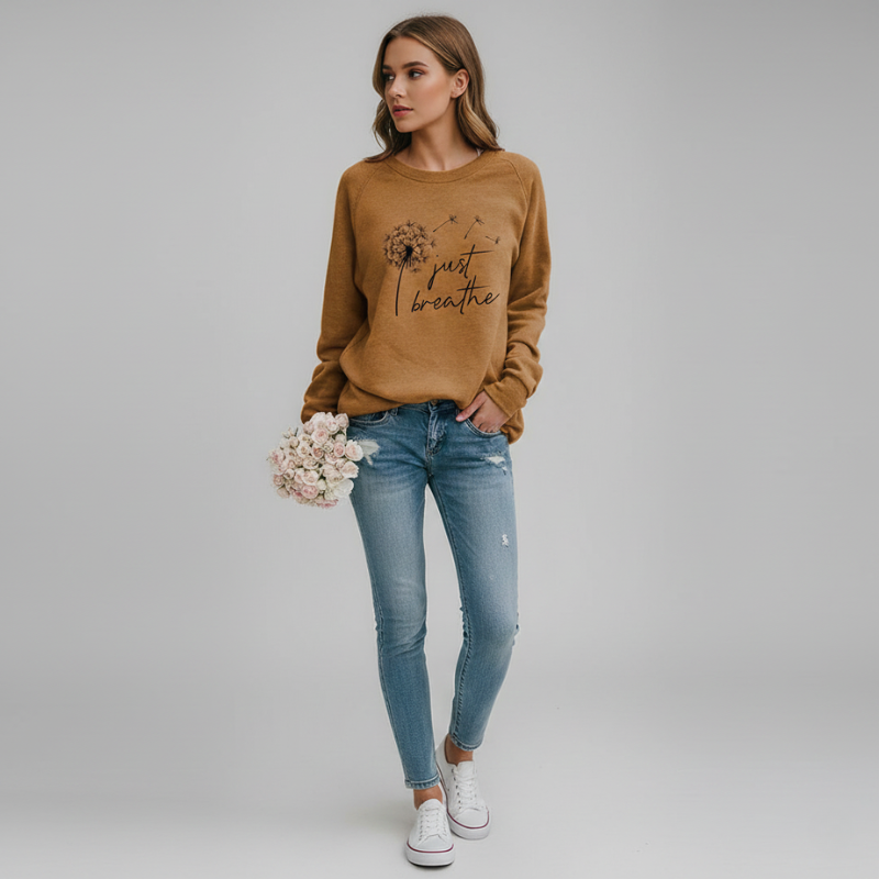 Woman wearing a brown sweatshirt with text and graphics, blue jeans, and white sneakers on a plain background