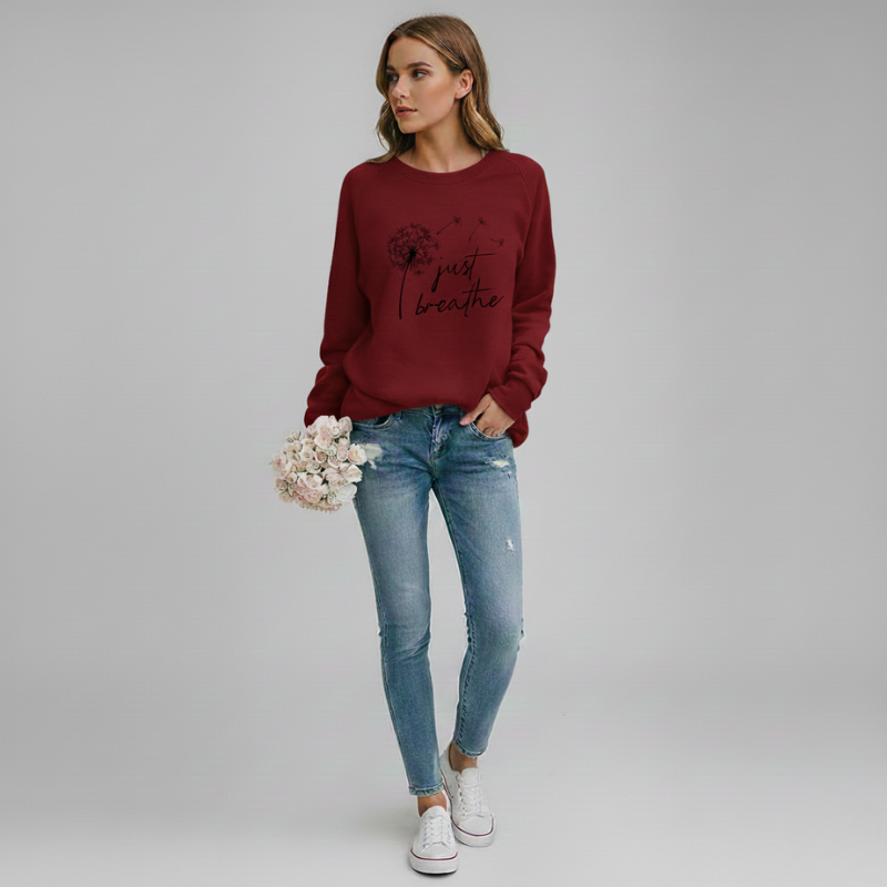 Woman wearing a red sweatshirt with text and blue jeans, standing against a plain background