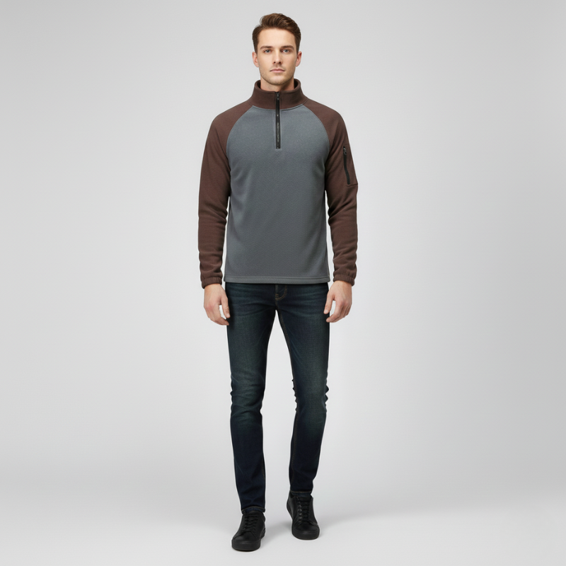 Man wearing a gray and brown pullover with black jeans on a light gray background