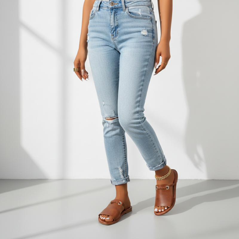 Person wearing light blue jeans and brown sandals on a white background
