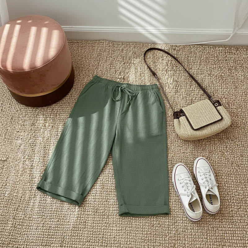 Green shorts, white sneakers, and a beige handbag on a carpeted floor.