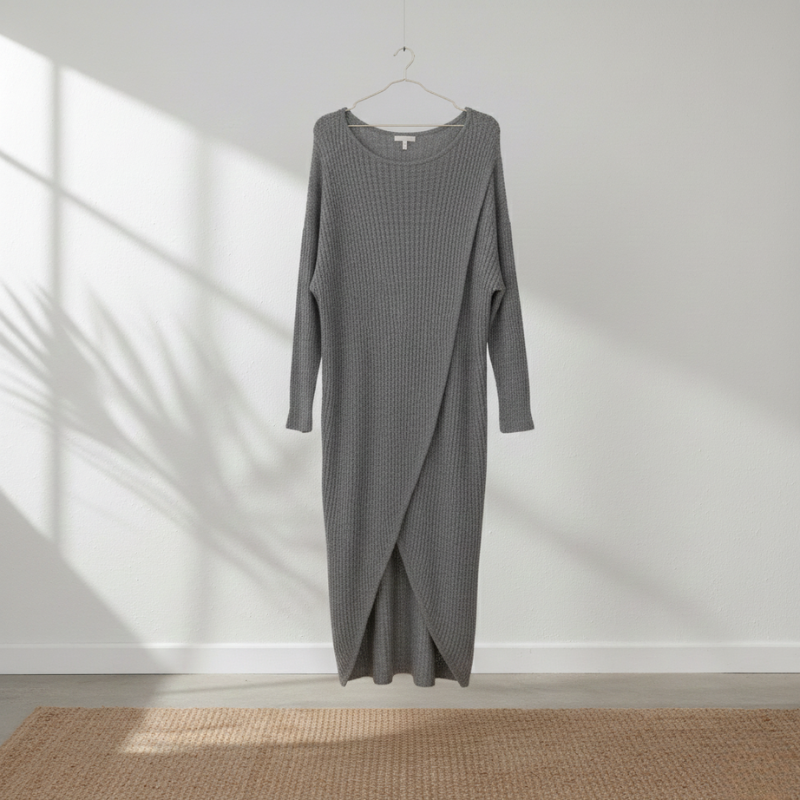 Gray knit dress on a hanger against a white wall with sunlight casting shadows.