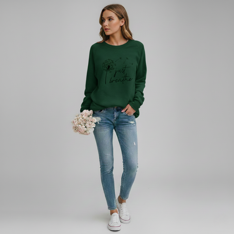 Woman wearing a green sweatshirt with text and blue jeans, holding flowers against a plain background