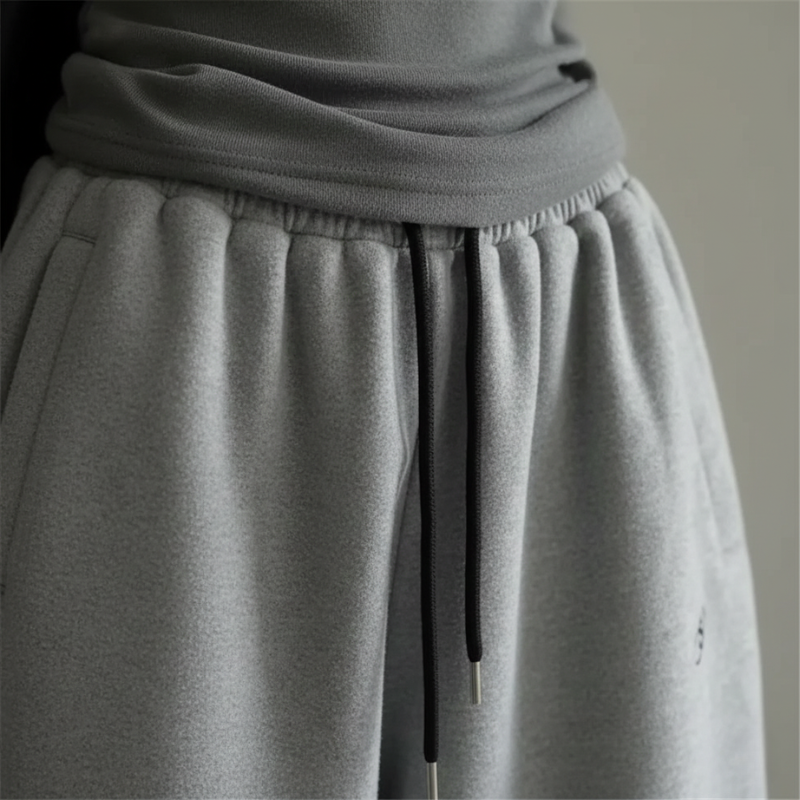 Close-up of gray knit pants showing elastic waistband, soft fabric texture, and gathered stitching.