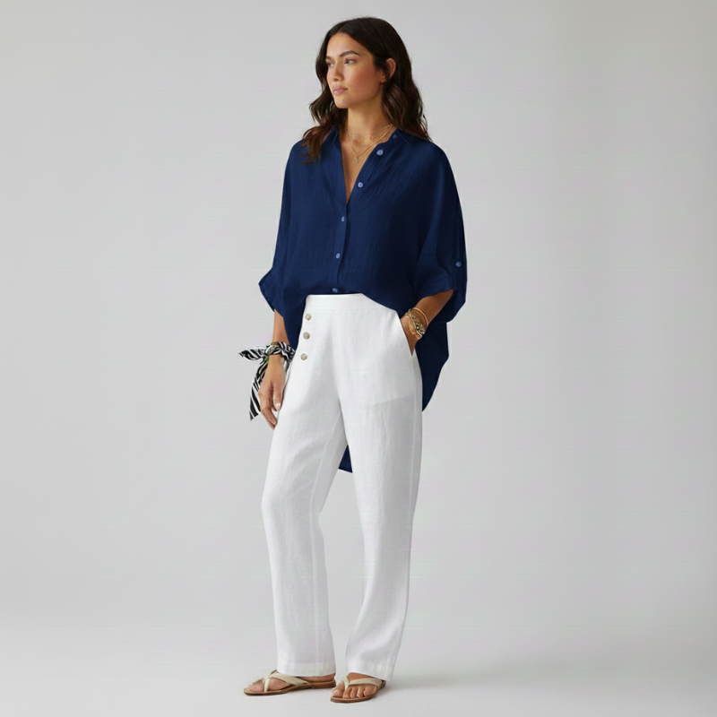 Woman wearing a navy blue shirt and white pants on a plain background