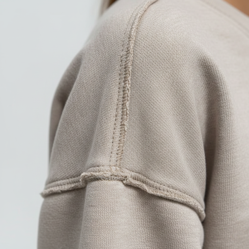 Close-up of a beige sweater sleeve with a plain background