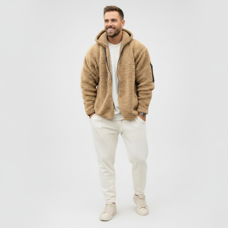 Male model wearing a beige teddy fleece jacket paired with light trousers in a studio environment.
