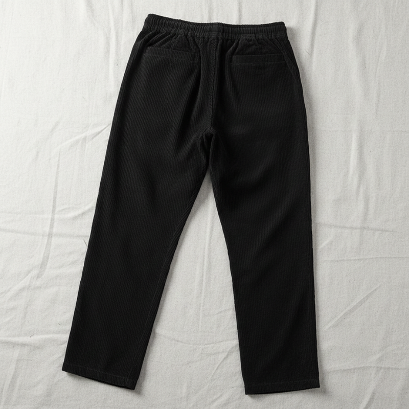 Flatlay of men’s black casual pants displayed on a neutral background.
