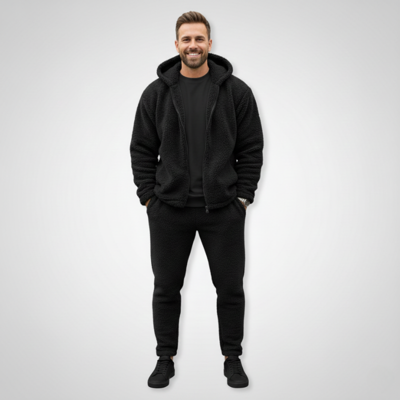 Man wearing a black fleece jacket styled with dark pants in a clean studio setting.