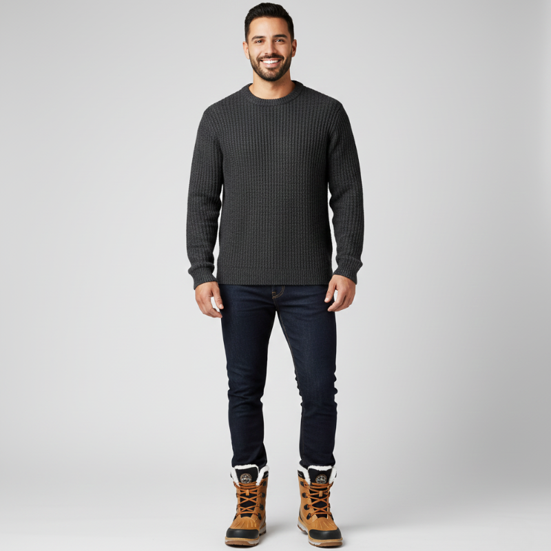 Man wearing a black outdoor jacket paired with dark pants and boots in a clean studio.