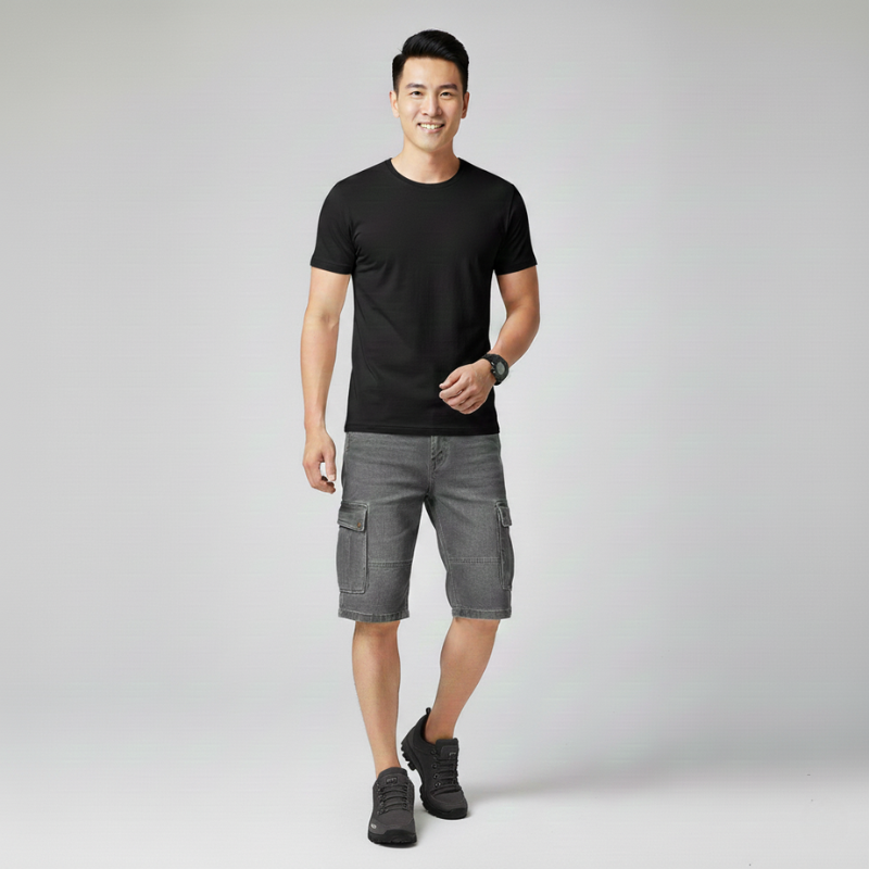 Male model wearing hiking shoes with a black t-shirt and shorts in a studio environment.