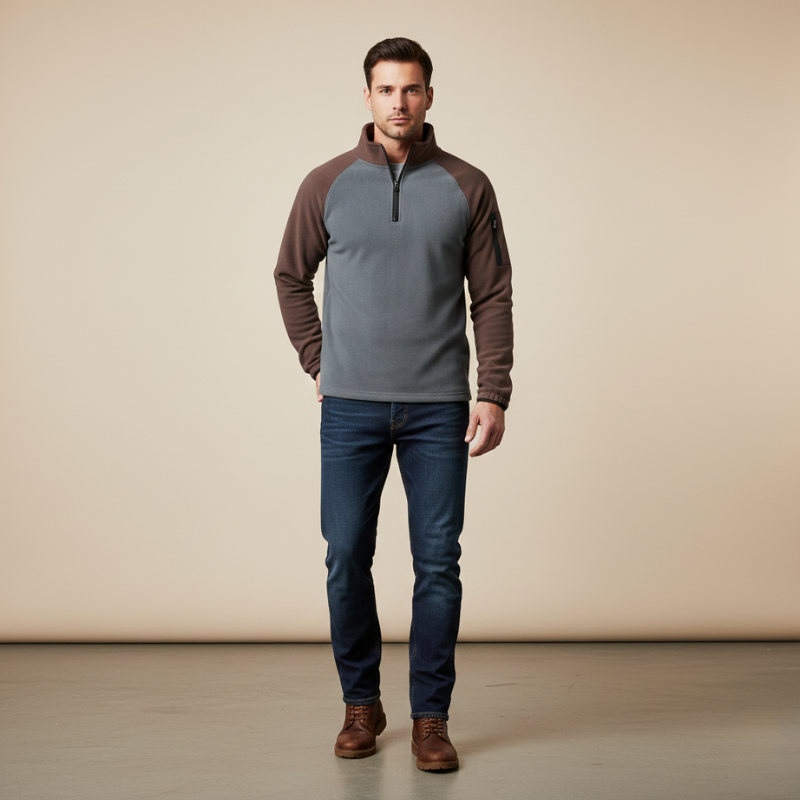 Man wearing a gray and brown pullover with blue jeans on a beige background