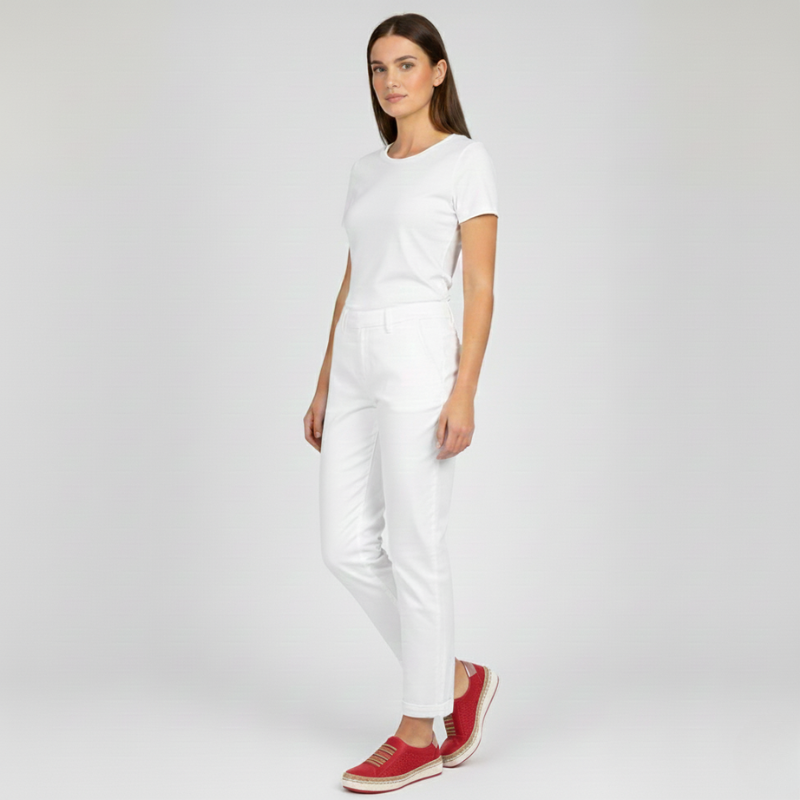 Woman wearing a white outfit with red shoes on a plain background