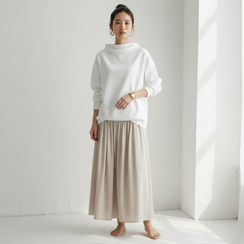 Woman wearing a white sweater and beige skirt in a minimalistic setting