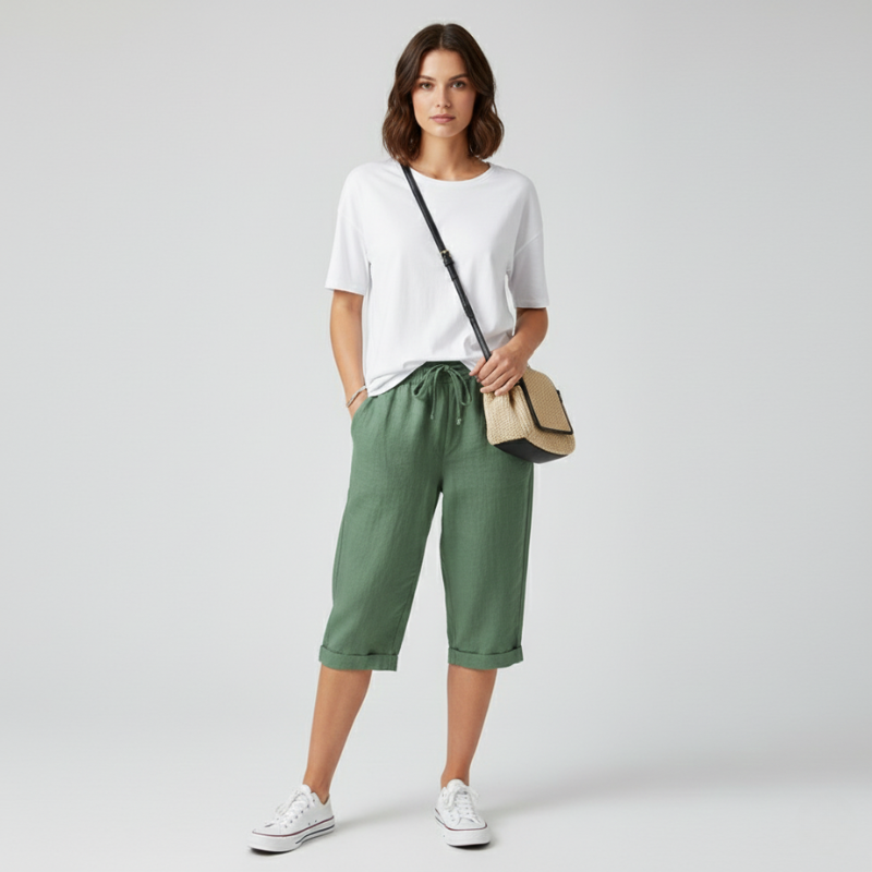 Woman wearing a white t-shirt, green pants, and white sneakers on a light gray background