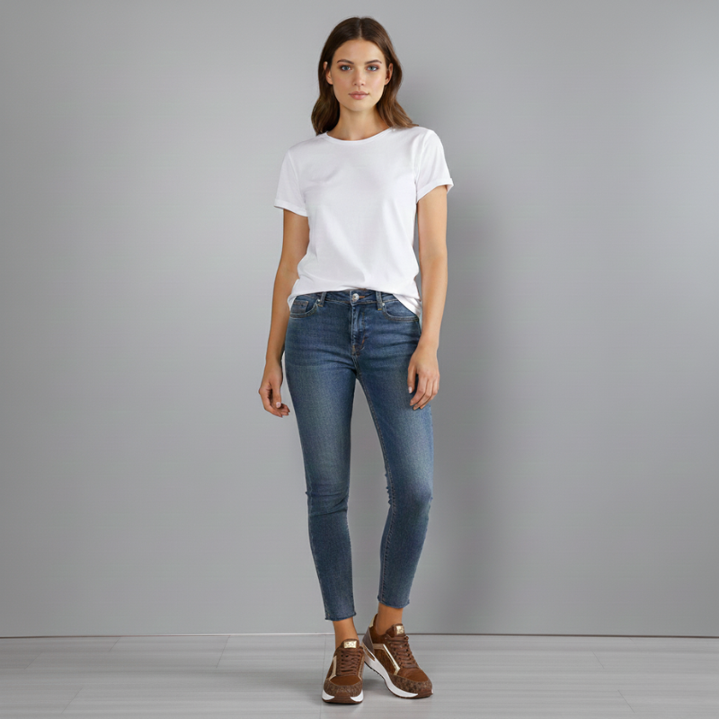 Woman wearing a white t-shirt and blue jeans against a gray background