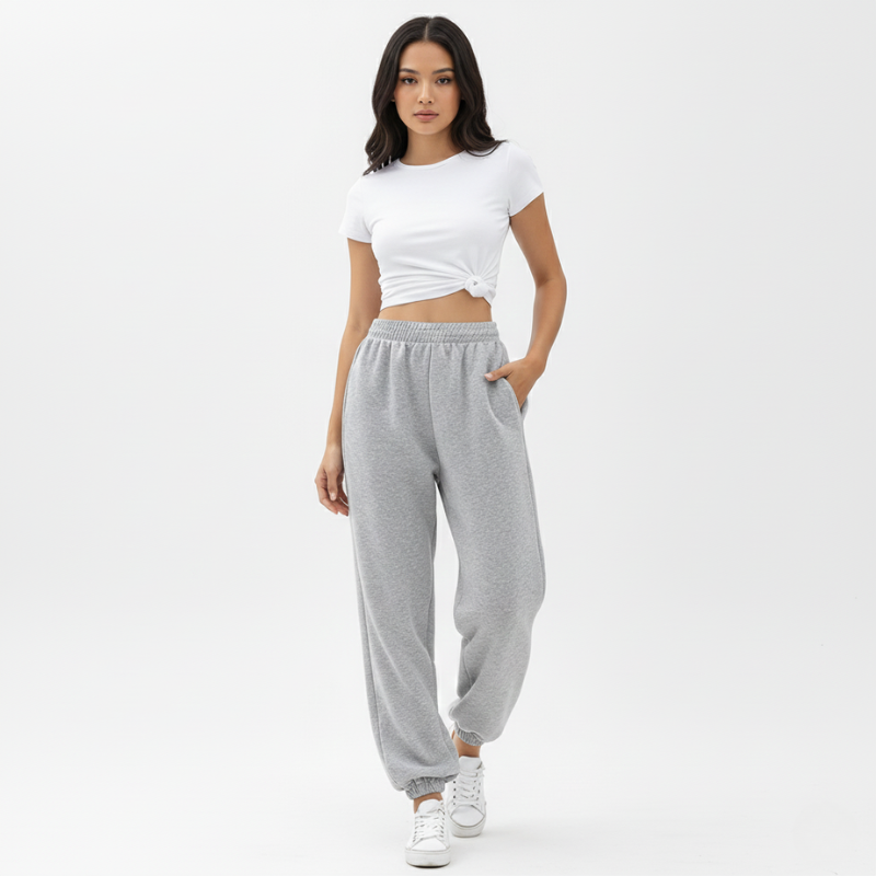 Woman wearing a white crop top and gray sweatpants on a white background