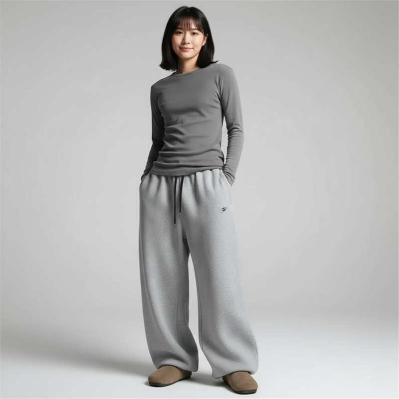 Woman wearing a gray knit long-sleeve top with matching wide-leg pants in a studio setting.