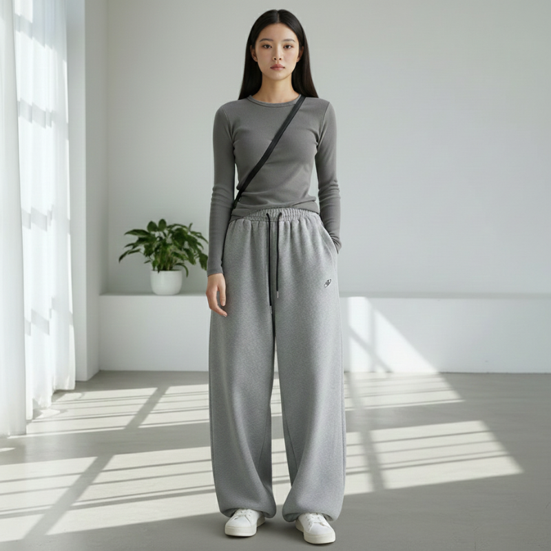 Woman standing near a window wearing a gray knit lounge set in natural daylight.