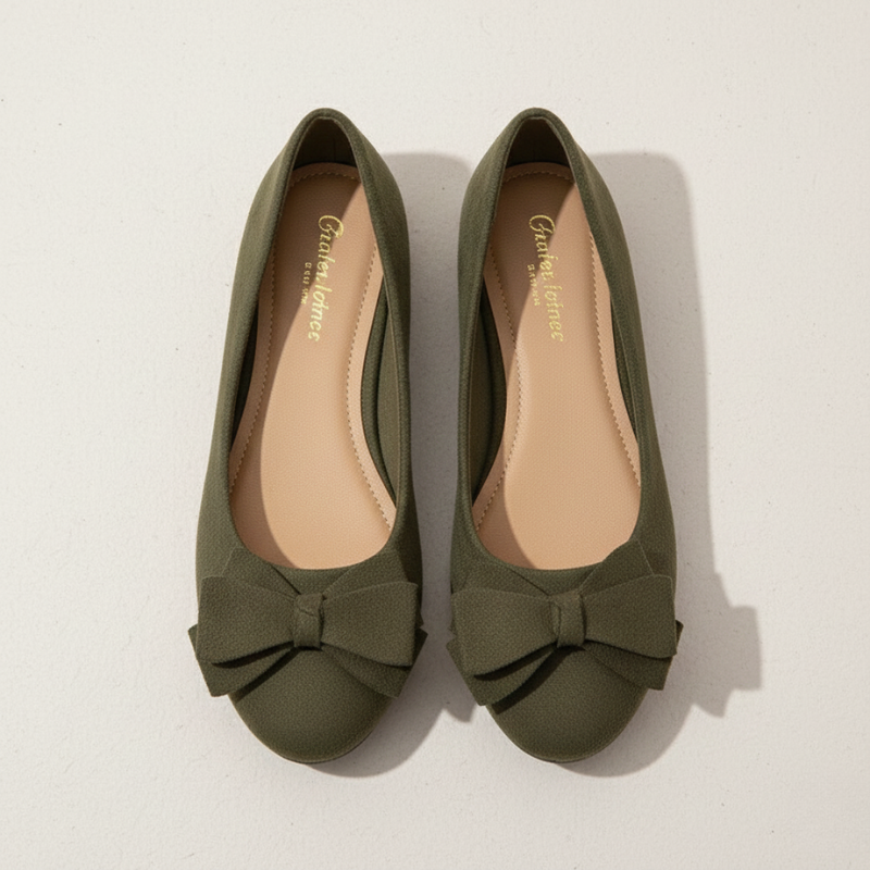 Pair of green flat shoes with a bow on a light background