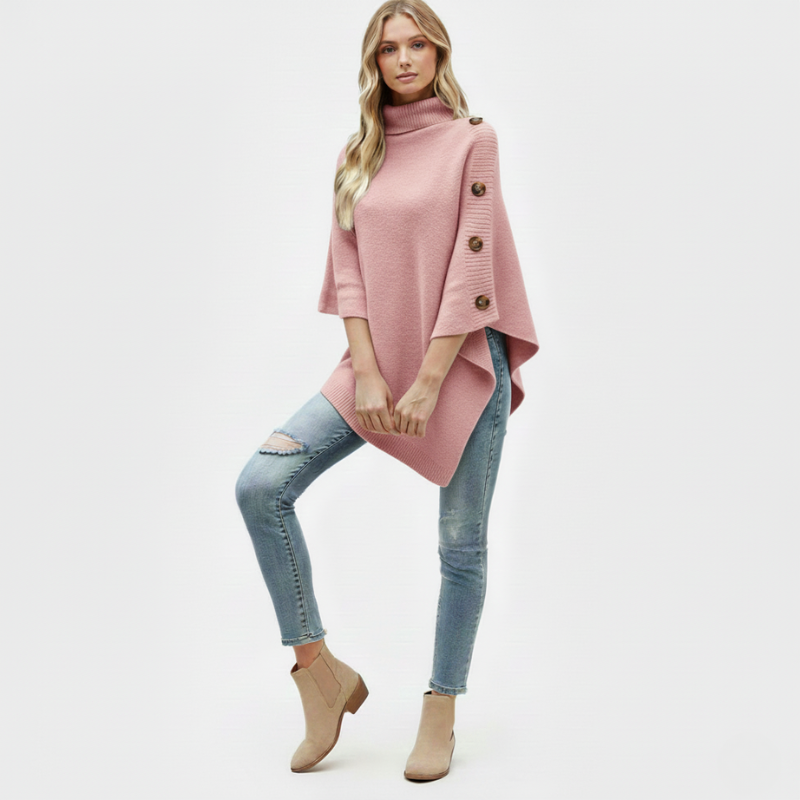 Woman wearing a pink poncho with buttons, light blue jeans, and beige boots on a white background