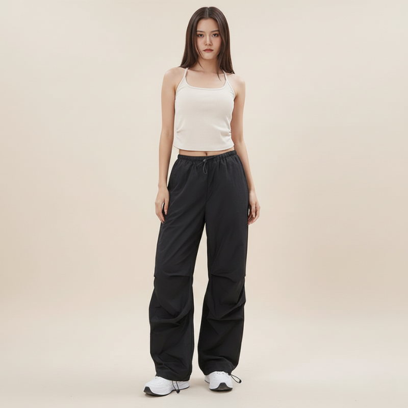 Woman wearing a white tank top and black pants on a beige background