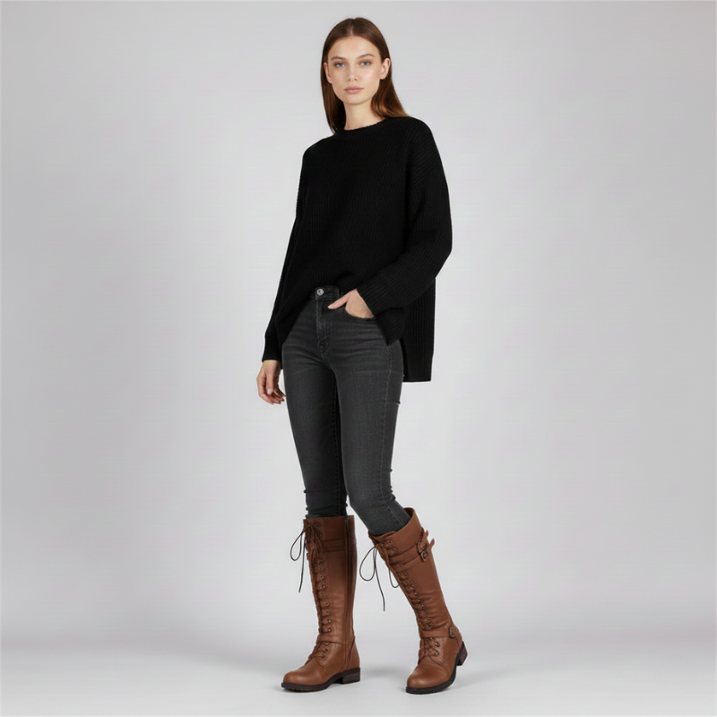 Full-body image of a woman wearing tall brown lace-up boots styled with a black oversized sweater.