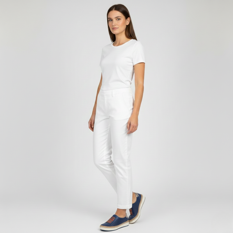 Woman wearing a white outfit with navy shoes on a light gray background