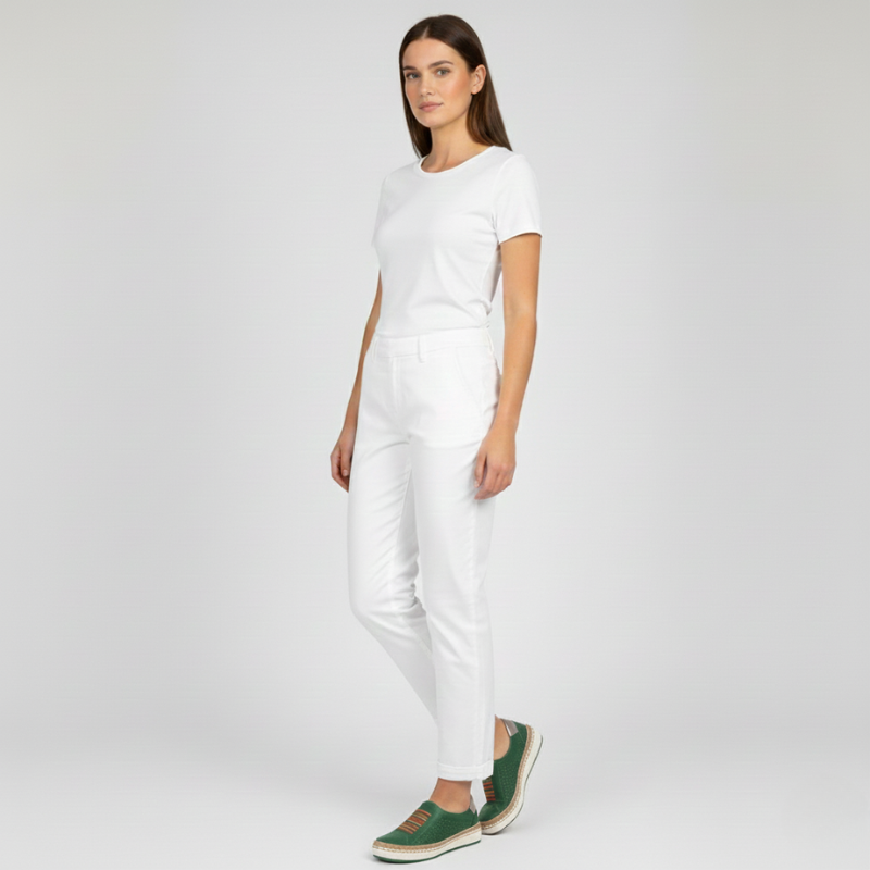 Woman wearing a white outfit with green shoes on a light gray background