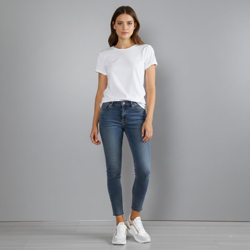 Woman wearing a white t-shirt and blue jeans against a gray background