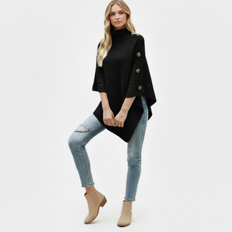 Woman wearing a black poncho with button details, light blue jeans, and beige ankle boots on a white background.